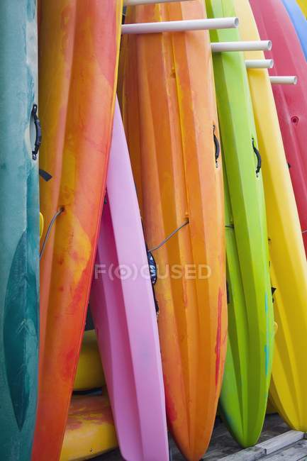 Colorful kayaks stacked up against wall — Stock Photo