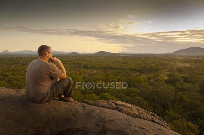 Junger Mann sitzt auf Felsen — Stockfoto