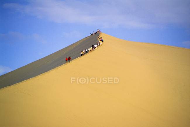 Gente escalando la duna de arena - foto de stock