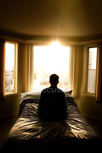 Вид сзади на человека, сидящего в одиночестве в спальне — стоковое фото