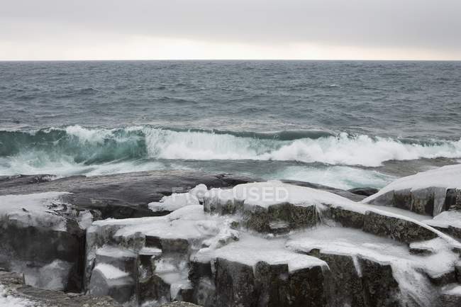 Хвилі і гуркотом проти Ice покриті порід — стокове фото