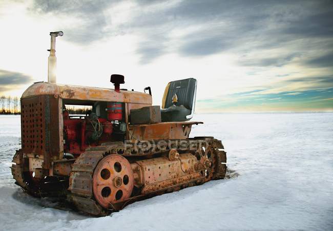 Alter Traktor auf Schnee geparkt — Stockfoto