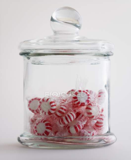Doces de hortelã-pimenta em frasco de vidro no fundo branco — Fotografia de Stock
