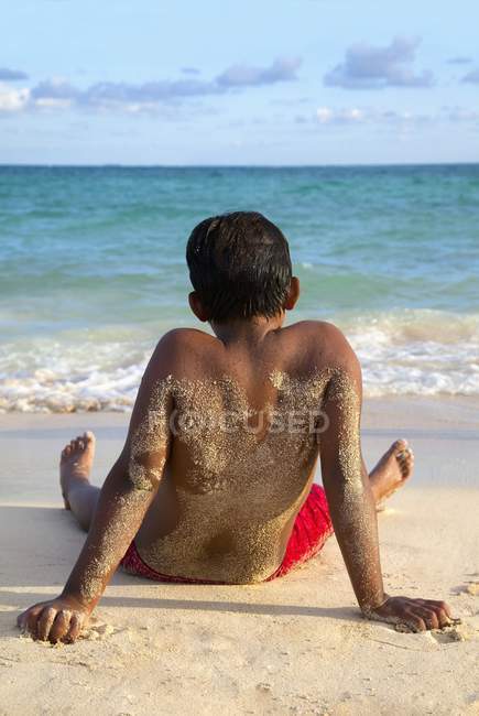 Ragazzo seduto sulla spiaggia — Foto stock