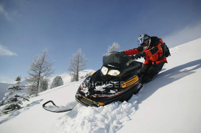 Homem dirigindo snowmobile na encosta coberta de neve — Fotografia de Stock