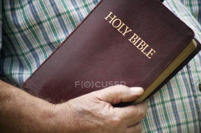 Person in shirt Holding Bible — Stock Photo
