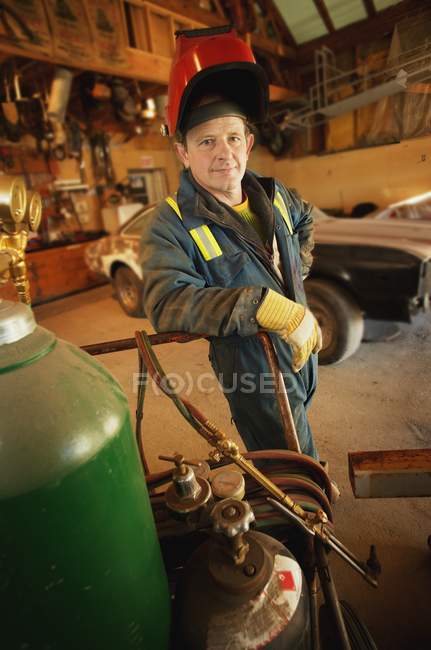 Portrait of male welder standing in front of car — Stock Photo