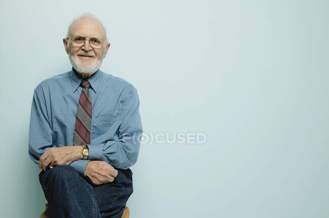 Портрет пожилого человека, сидящего и улыбающегося перед камерой — стоковое фото