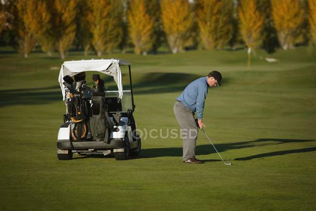 Caucásico mediano adulto golfista al lado de golf coche en curso - foto de stock