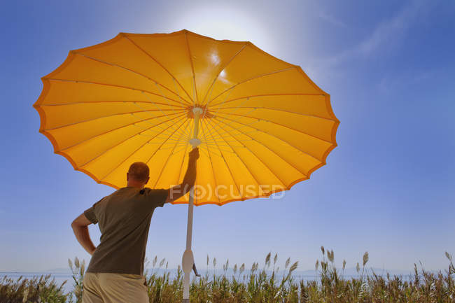 Hombre de pie bajo el paraguas - foto de stock