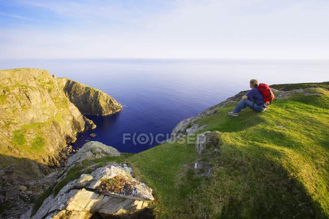 Backpacker  sitting on grassy hill — Stock Photo