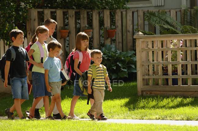 Les écoliers marchent sur l'herbe verte — Photo de stock