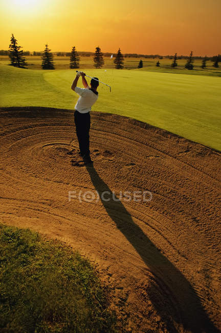 Vista trasera del golfista que toma el oscilación del bunker del golf - foto de stock