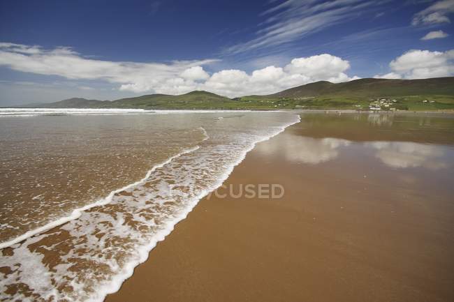 Playa de arena con agua ondulada - foto de stock
