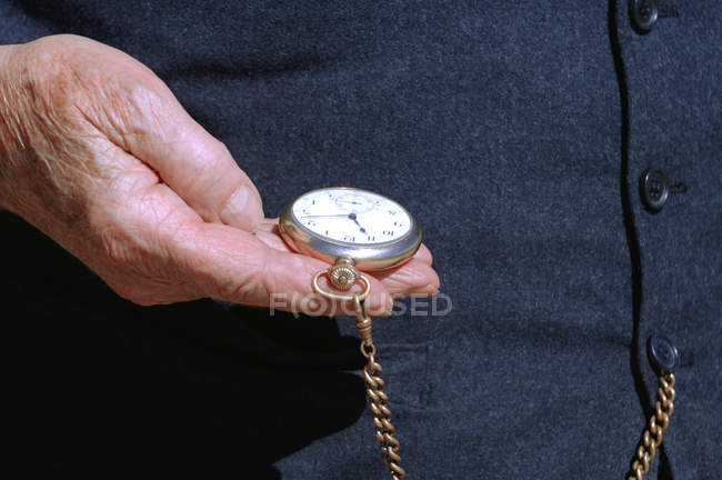 Abgeschnittenes Bild einer verblühten Hand, die eine Taschenuhr hält — Stockfoto