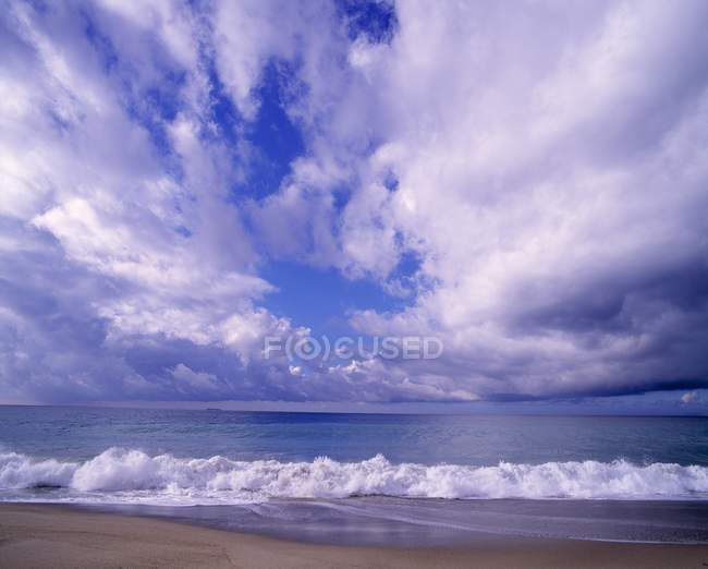 Playa de arena con agua ondulada - foto de stock