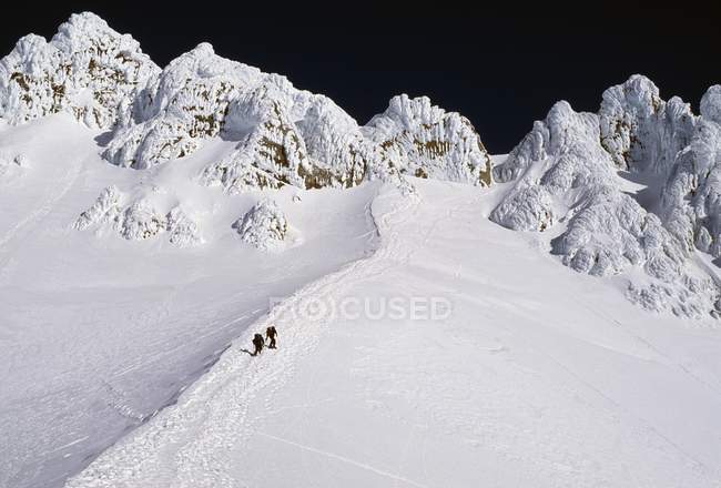 Escaladores distantes en la nieve - foto de stock