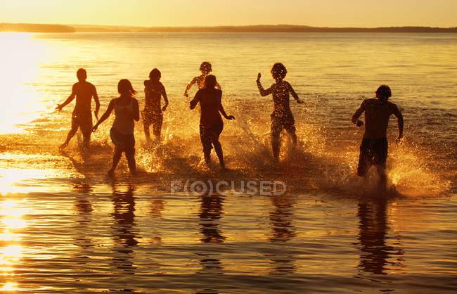 Gruppo di persone che corrono attraverso l'acqua — Foto stock