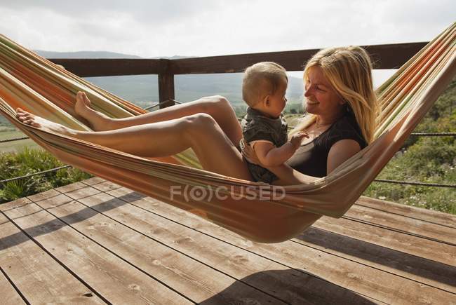 Uma mãe em uma rede com seu filho jovem — Fotografia de Stock