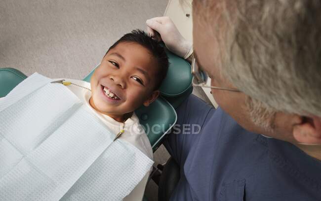 Усміхнений хлопчик у стоматологічному кріслі, високий кут зору — стокове фото