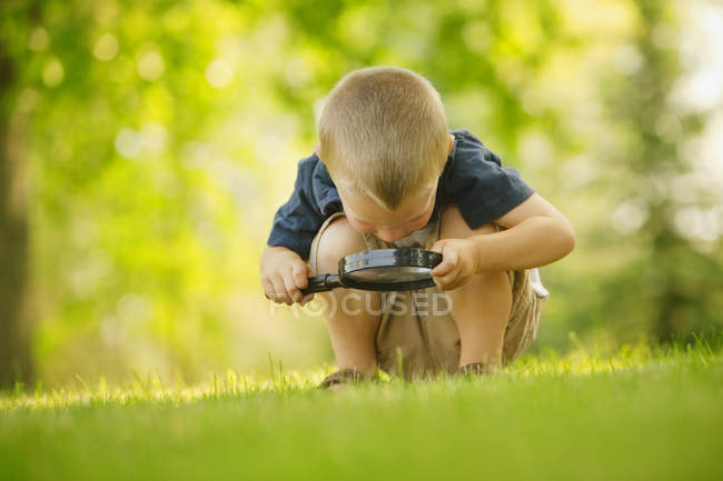 Мальчик с лупой на улице — стоковое фото