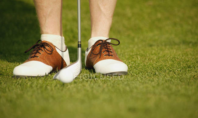Image recadrée de jambes masculines dans des chaussures de golfeurs avec club sur le parcours — Photo de stock