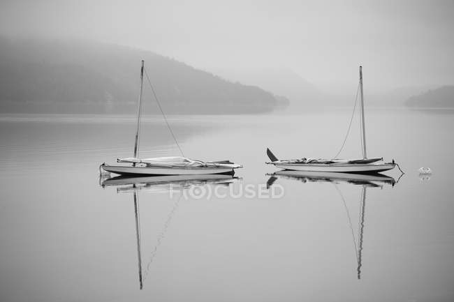 Two sailboats reflected in misty lake — Stock Photo