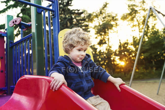 Bambino che gioca al parco giochi al tramonto; St. Albert, Alberta, Canada — Foto stock