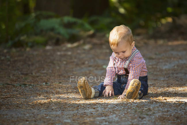Young boy sitting on path in park, Langley, Canada — Stock Photo