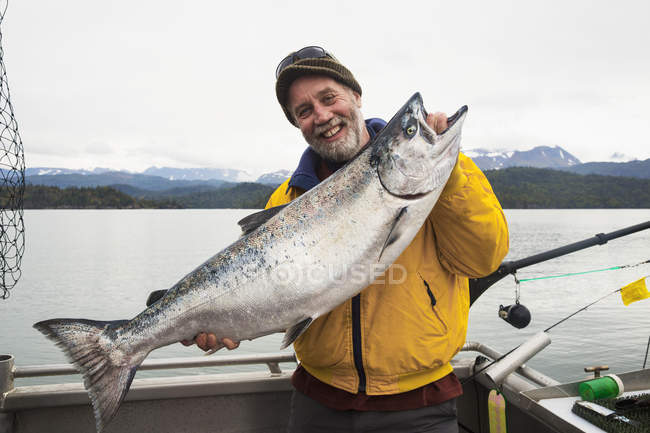 Чоловік тримає зловив рибу з лососем на човні — стокове фото