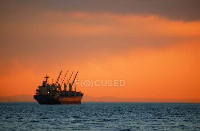 Frachter auf hoher See bei Sonnenuntergang — Stockfoto