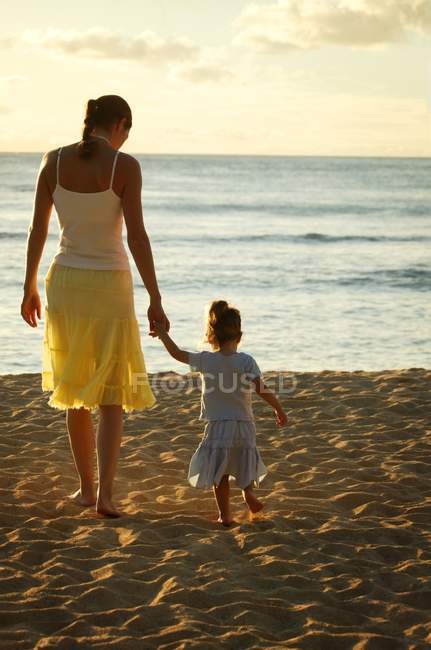 Mutter und Tochter am Sandstrand Händchen haltend — Stockfoto