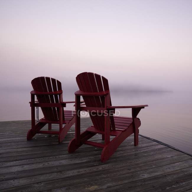 Два красных кресла Адирондак — стоковое фото