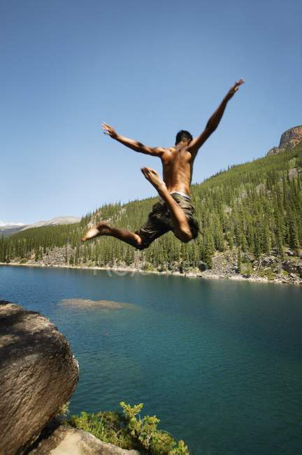 Giovane uomo che salta nel lago — Foto stock