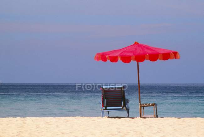 Chaise et parapluie sur la plage — Photo de stock