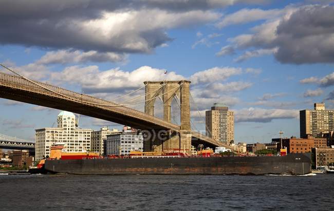Barcaza pasando por debajo del puente de Brooklyn - foto de stock