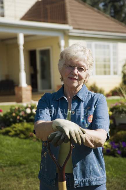Старша жінка садівник позує в саду з лопатою — стокове фото