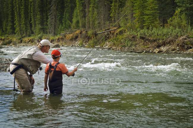 Padre e hijo pescando en el río de montaña. Nordegg, Alberta, Canadá - foto de stock