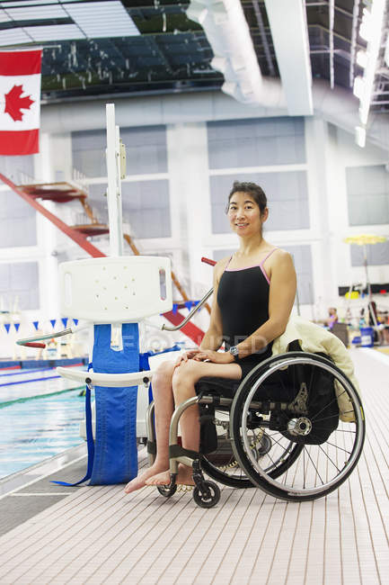 Woman in wheelchair sitting at at edge of swimming pool — Stock Photo