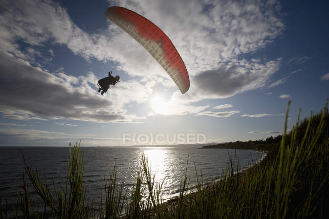 Mann fliegt mit Gleitschirm an Klippen entlang — Stockfoto
