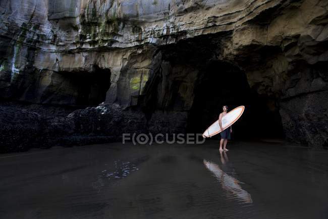 Surfista dentro una grotta a Muriwai, Nuova Zelanda — Foto stock