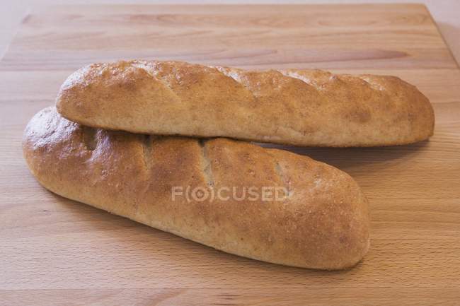 Dos panes de pan al horno en el primer plano de la tabla de cortar - foto de stock