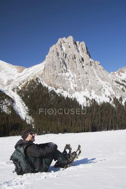 Mann in Schneeschuhen sitzt — Stockfoto