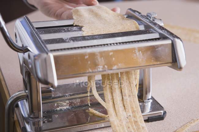 Nudelmaschine zur Herstellung von Pasta über hölzerner weißer Oberfläche — Stockfoto