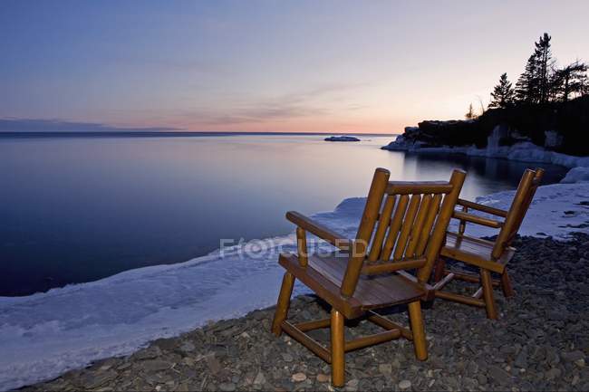 Два стула на краю воды — стоковое фото