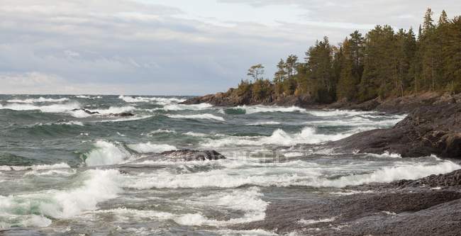 Rompiendo olas en la costa rocosa - foto de stock