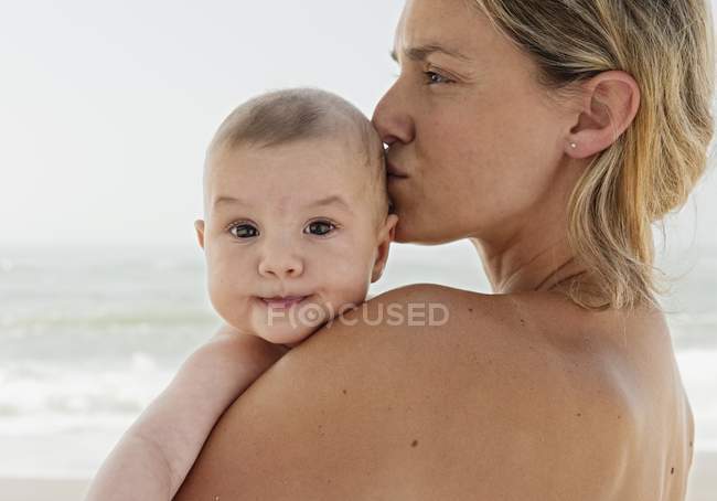 Madre sosteniendo su bebé cerca con beso - foto de stock