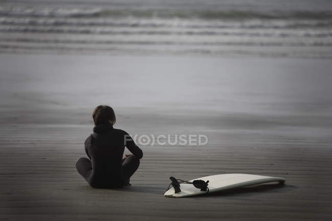 Surfista sentado na praia — Fotografia de Stock
