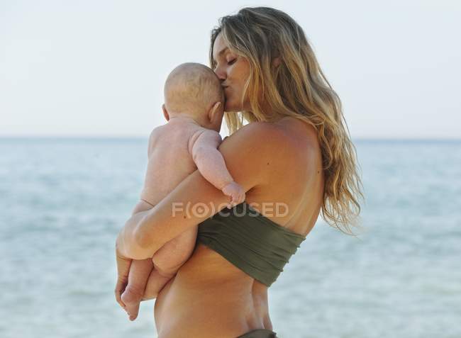 Mãe segurando seu bebê perto com beijo — Fotografia de Stock