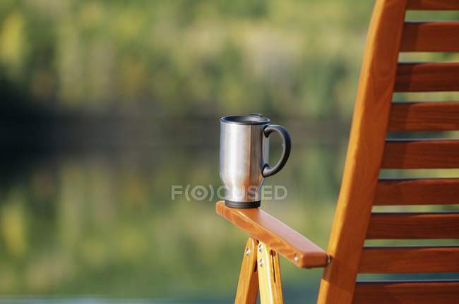 Caneca de café na cadeira da plataforma contra fundo desfocado — Fotografia de Stock